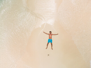 The guy lies on a sandy beach on a tropical island.