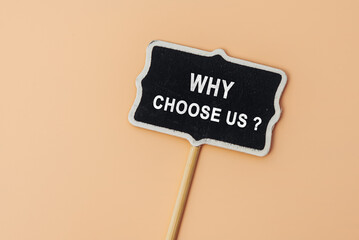 Why choose us - text on a small chalkboard on a beige background. Top view. Concept meaning list of...