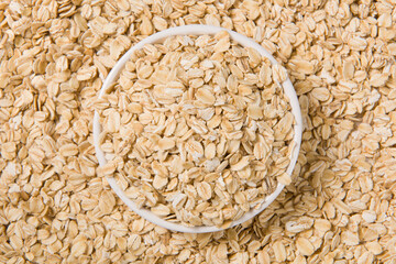 Rolled oat, oat flakes in dish background or texture.