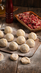 Semi-finished manti oriental dumplings on wooden board with flour