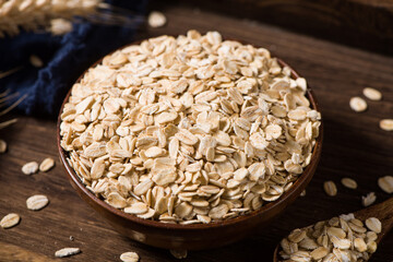 Dry rolled oat flakes oatmeal in plate on wooden table