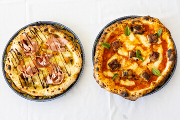 Due pizze tradizionali napoletane fotografate dall'alto su una tovaglia bianca di una pizzeria...