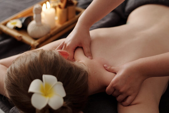 Hands of masseuse massaging neck and shoulders of young woman