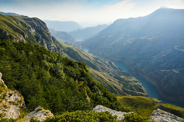 A beautiful landscape of mountains with bushes, rocks and a blue river on a summer day. Sulak Canyon.