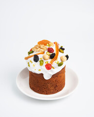 A cake with candied fruits and icing on a white plate on a white isolated background. The concept of the Easter holiday.