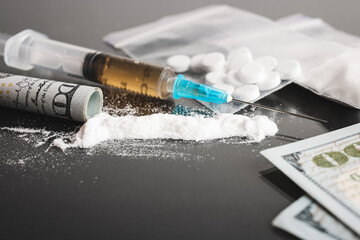 Drugs on dark background, cocaine or heroin white powder, white pills, syringe with a dose and us...