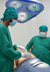 Group of surgeons and nurse in surgical green gown working at operating room of the hospital. Medical Team performing Surgical operation.