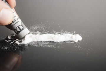 Snorting cocaine, white powder line, rolled up dollar bill, black background