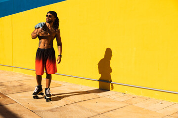 Black man on roller skates riding outside. Urban man posing with roller skates.