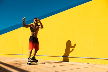 Black man on roller skates riding outside. Urban man posing with roller skates.