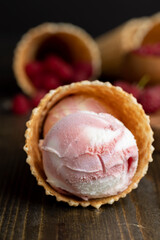 Waffle cone with white pink cream ice cream and raspberries