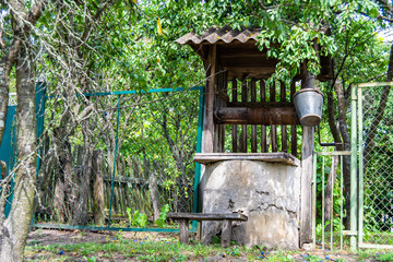 Old well with iron bucket on long forged chain for clean drinking water