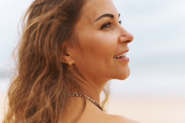 Close up portrait. Young adorable woman is standing and relaxing on the sand beach at the wind