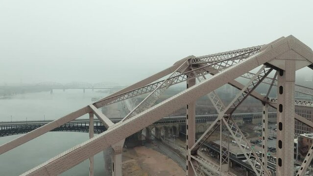 Aerial rise up truss of Martin Luther King Bridge, view of St. Louis in fog.