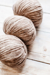 Three coils of beige thread on a light background for knitting
