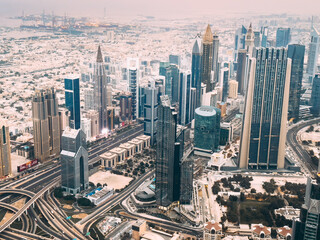 Fototapeta na wymiar Aerial view of Downtown Dubai with roads, Dubai Mall and the fountain at sunrise, from Burj Khalifa observatory deck in United Arab Emirates