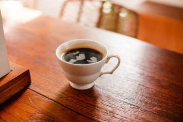 Black hot coffee in a white cup on a wooden table. Sturdy Americano on a wooden background