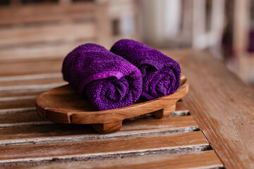 Obraz na płótnie Canvas Two wet purple towels for hands and face on a wooden stand. The concept of body care, massage and spa