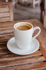 Strong hot coffee in a white large mug on a wooden table
