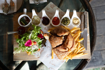 Eisbein with braised cabbage, salad and Yummy french fries with set of souces in bowl. Traditional Oktoberfest smoked pork knuckle eisbein, sauce and baked spices potato. German festival food concept.