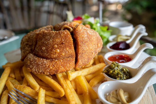 Eisbein with braised cabbage, salad and Yummy french fries with set of souces in bowl. Traditional Oktoberfest smoked pork knuckle eisbein, sauce and baked spices potato. German festival food concept.