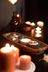 Wooden bowl with stones and burning candles in massage room in spa salon