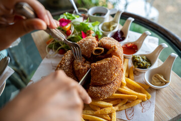 Eisbein with braised cabbage, salad and Yummy french fries with set of souces in bowl. Traditional Oktoberfest smoked pork knuckle eisbein, sauce and baked spices potato. German festival food concept.