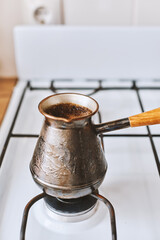 Preparation hot tasty beverage coffee in cezve in boiling water on small fire - 576633553