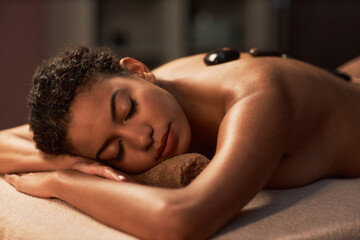 Obraz na płótnie Canvas Young woman fell asleep when getting hot stones spa procedure