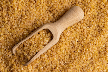 Not cooked wheat porridge with a wooden spoon