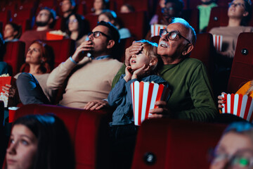 Obraz premium Grandfather and granddaughter watching scary movie in cinema.