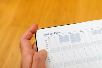 Obraz premium Male hand on the new 2024 year planner agenda with January, February, March, April, May months and empty fields