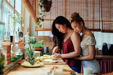 Young multiracial lesbian couple preparing food in the kitchen