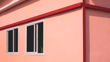 Sunlight and shadow on surface of glass sliding windows on orange concrete wall with red edge of...