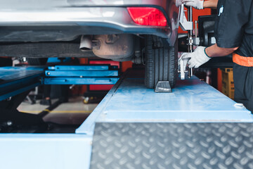 In the service station workshop, a car is on a stand with sensors on the wheels being checked for...