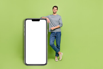 Full size photo of cool confident man promote recommend you new phone isolated on green color background