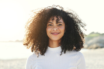 Black woman, face and portrait at beach for vacation, freedom and smile with natural hair and beauty. Happy young model person outdoor in nature for peace, travel and time to relax on sunset holiday