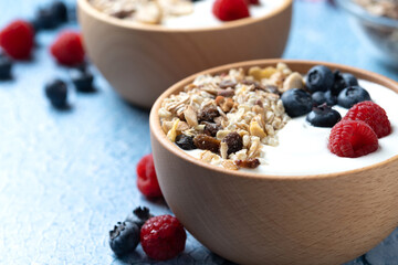 Yogurt with berries and muesli for breakfast in bowl on blue background