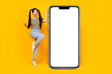 Full body photo of woman celebrate her lottery winning stand next to big phone display isolated on yellow color background