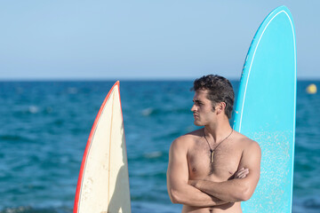 Hispanic surfer guy standing on the beach in a swimsuit looking at the camera next to two...