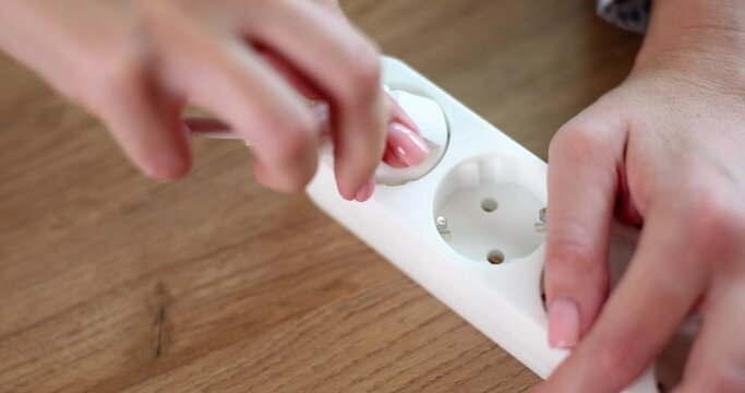 Closeup of woman hand inserting plug into socket