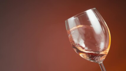 Rose wine waving in a glass against the amber colored background. Slow motion.  - Powered by Adobe