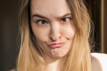 Horizontal shot of funny humorous playful young European woman making grimace, trying to touch nose with her lips. People, youth, leisure, joy, fun, spontaneous and entertainment concept