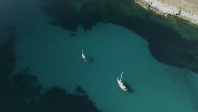 Aerial view of a sailing boat sailing along the coast in Sicily, Italy.