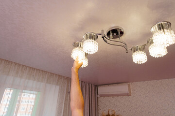a man's hand will replace the bulbs in the chandelier lampshades. 