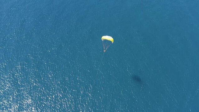 Aerial view of a person doing parasail with a motorboat along the coast in Sicily, Italy.