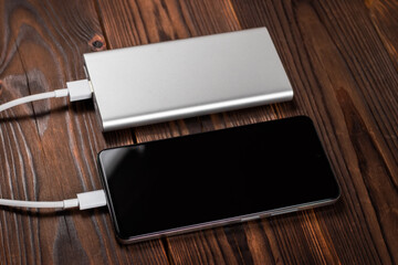 Powerbank and charge smartphone on wooden table