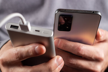 The men hand hold the phone and charger, powerbank and smart phone is connecting, energy