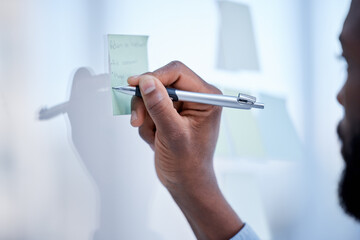 Black man, hands and writing for schedule planning, brainstorming or tasks on glass board at office. Hand of African American male with pen to write project plan, idea or sticky note for strategy