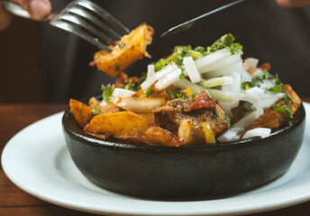 Man eating Beef stew with potatoes, carrots and herbs on black background with copy